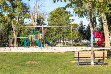 Deserted playgrond for children with slides and swings in a public park on a sunny autumn day
