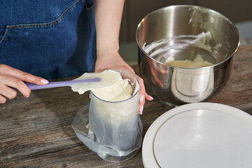 a woman's hand puts whipped curd cream for a cake into a pastry bag