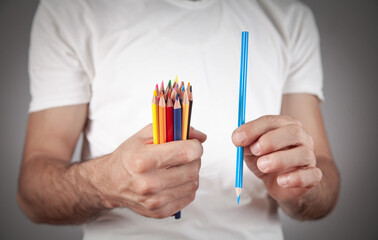 Caucasian man holding colored pencils.
