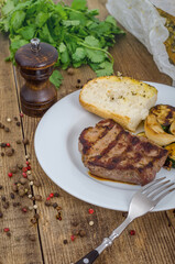 White plate with steak and bread on table