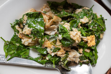 Stir-fried Malindjo Leaves with Egg serve on white plate.