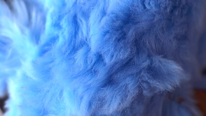 Blue faux fur. Long pile. Children's toy. Piece of clothing. Animal protection. Substitute for natural fur. Fabric production. Close-up. Object rotation.