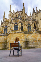Woman sitting on a bench contemplating the impressive cathedral of Leon, Spain.