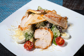 Italian salad with chicken fillet eggs and cherry tomatoes. Caesar on white plate 