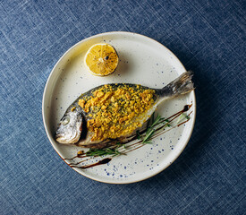 Grilled Dorado on white plate with lemon and spices