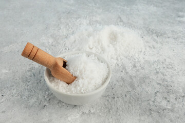 Salt, white sugar in bulk in a bowl, wooden scoop, spoon. Grey background. The concept of a shortage of bulk products, due to the global crisis and the war in Ukraine