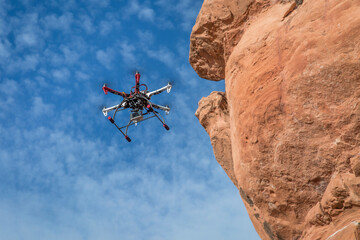 home made hexacopter drone flying with a small camera along sandstone canyon cliff