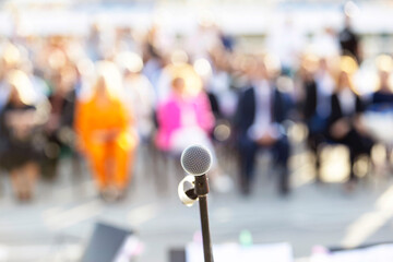 Publicity or celebration event, microphone in the focus against blurred audience in the background