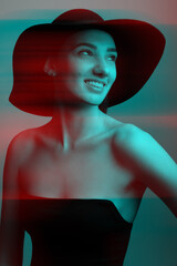 Elegant sexy woman with sile wearing black wide hat and black dress. RGB color split effect. RGB effect make reflection of model face in red and blue colors. Abstract and futuristic looking style