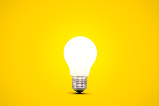 Glowing light bulb isolated on a bright yellow background.