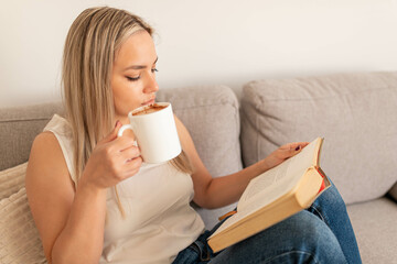 Grey cozy bed and a beautiful girl, reading a book, concepts of home and comfort