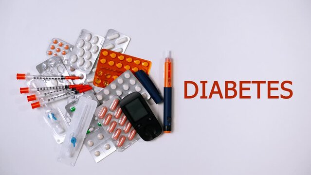 Medication pills and capsules, catheter, insulin syringes and glucometer lie on white background. Syringe pen with hormone insulin rolls to side and word appears - Diabetes. Video with animation, text