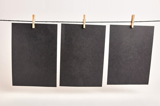 Sheets of black paper hung with clothespins on a rope on a white background. Black background for inscriptions or advertising images.
