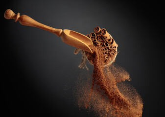 Cinnamon powder is poured out of the wooden spoon. - obrazy, fototapety, plakaty