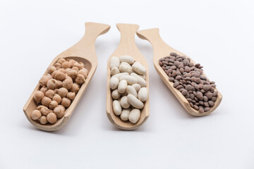 three wooden pallets with different legumes on a white background