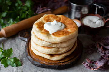 A hearty snack: a stack of fluffy tortillas with cheese and sour cream on a wooden plate. Tortillas with cheese for breakfast for the whole family. Close-up