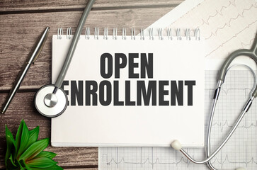 open enrollment sign on notebook with stethoscope and cardio charts