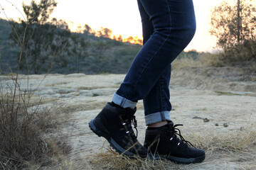 Legs with denim pants and black hiking boots in the middle of the field walk, pose, play, explore,...