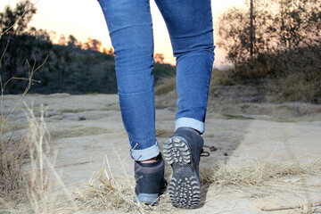 Legs with denim pants and black hiking boots in the middle of the field walk, pose, play, explore, discover and live in freedom

