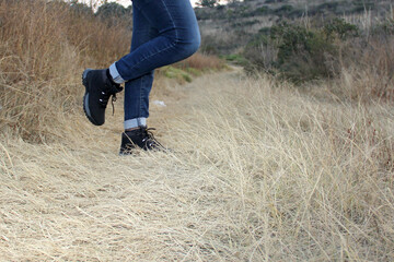 Legs with denim pants and black hiking boots in the middle of the field walk, pose, play, explore, discover and live in freedom
