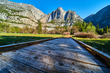 Frosty boardwalk in shade as sun hits cliffs and Upper Yosemite Falls in background