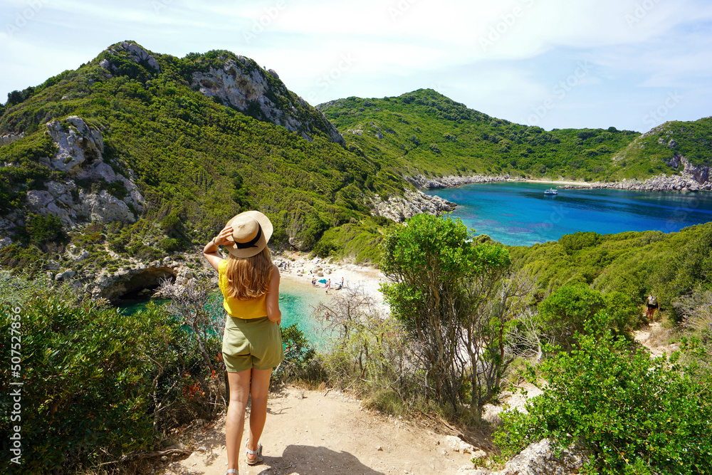 Wall mural discovering greece. hiker woman enjoying amazing lookout of porto timoni on corfu island, greece.