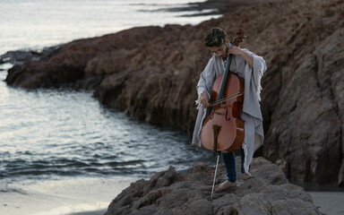 Young man Playing cello at the beach