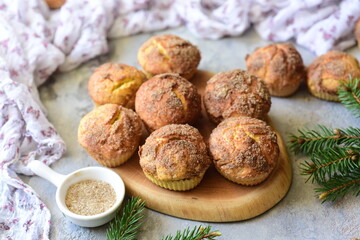 Obraz na płótnie Canvas Delicious dessert for a snack for the whole family: pumpkin cupcakes sprinkled with sugar. Pumpkin muffins with a crispy crust on a beautiful board on a gray background. Close-up