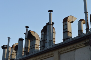 A pile of ventilation chimneys and steam vents on the roof of an old industrial production hall