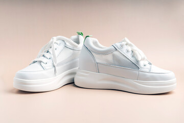 White sneakers with a net on the sides on a beige background