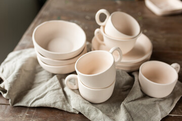 Ceramic pots, plates and cups in clay on wooden table. Eco friendly pottery set handmade