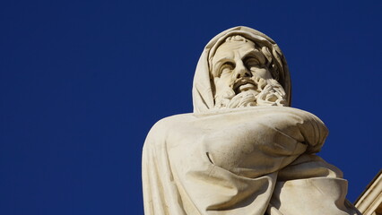 marble statue of a philosopher seen from below with blue sky. conceptual, descriptive image