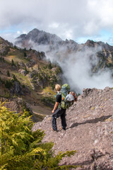Hiker looking at mountains and fog in summer