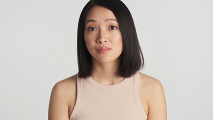 Portrait of woman raising eyebrows looking at camera over white background. Face expression