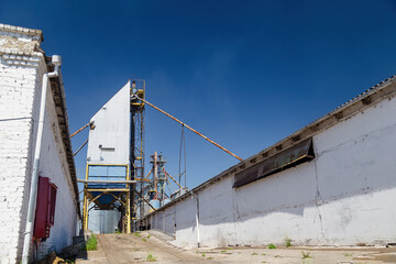 Place for loading of grain and crops in trucks from granary elevator storage before export, blue sky background.