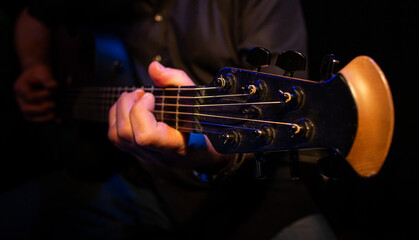 Selective shot of a musician playing on an acoustic guitar with his hands visible an focus on...