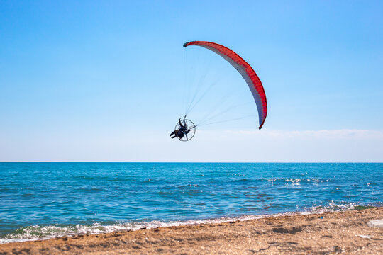 A man on a paraglider in the blue sky over the sea. Sports and passion for flying