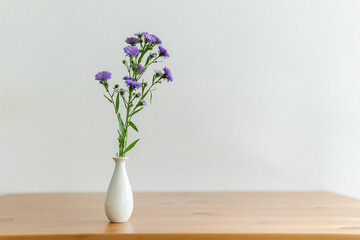 lilac flowers in a vase on a wooden background.