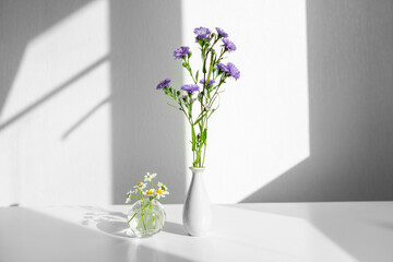 flowers in a vase. different flowers on a white table in sunlight.
