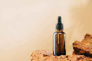 Natural medicine or aroma oil or beauty essence concept vial with dropper on stone stand with green plant and golden brown background. Face and body spa serum care concept banner