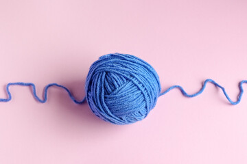Blue knitted wool on a pink background for knitting warm clothes and hobbies needlework