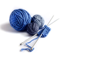 Blue knitted wool on a white background with knitting needles for knitting warm clothes, hobbies