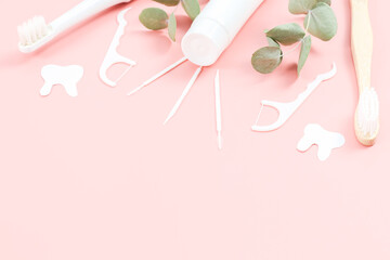 Bamboo toothbrushes, electric, tube of toothpaste, dental floss, toothpicks and chewing gums on a soft pink