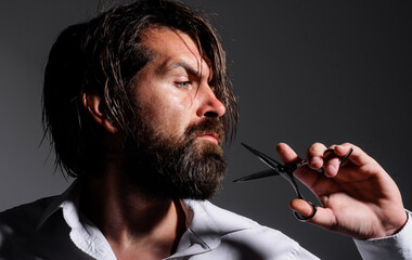 Bearded man with barber scissors. Mans haircut in barber shop. Beard styling and cut. Barbershop.