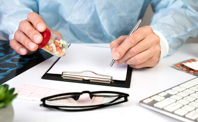 Close-up of the hands of a male doctor writing a prescription to a patient in a clinic. The concept of healthcare and medicine.