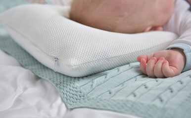 The baby sleeps on an orthopedic pillow, rear view