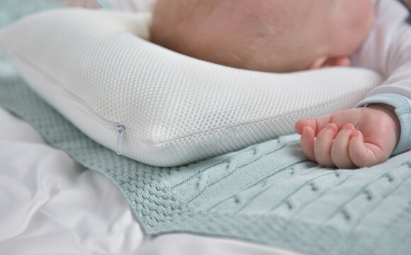 The baby sleeps on an orthopedic pillow, rear view