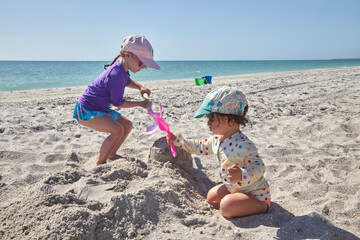 Two little girls playing in the sand on a family vacation at the beach