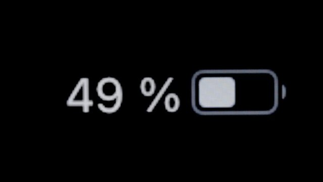 Timelapse - smartphone battery level indicator running low - from 100 to zero percent: close up macro of gadget display, screen, black background. Energy, technology, digital and time lapse concept