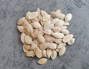 Closeup of white pumpkin seeds on a gray backround. Healthy fats, magnesium and zinc